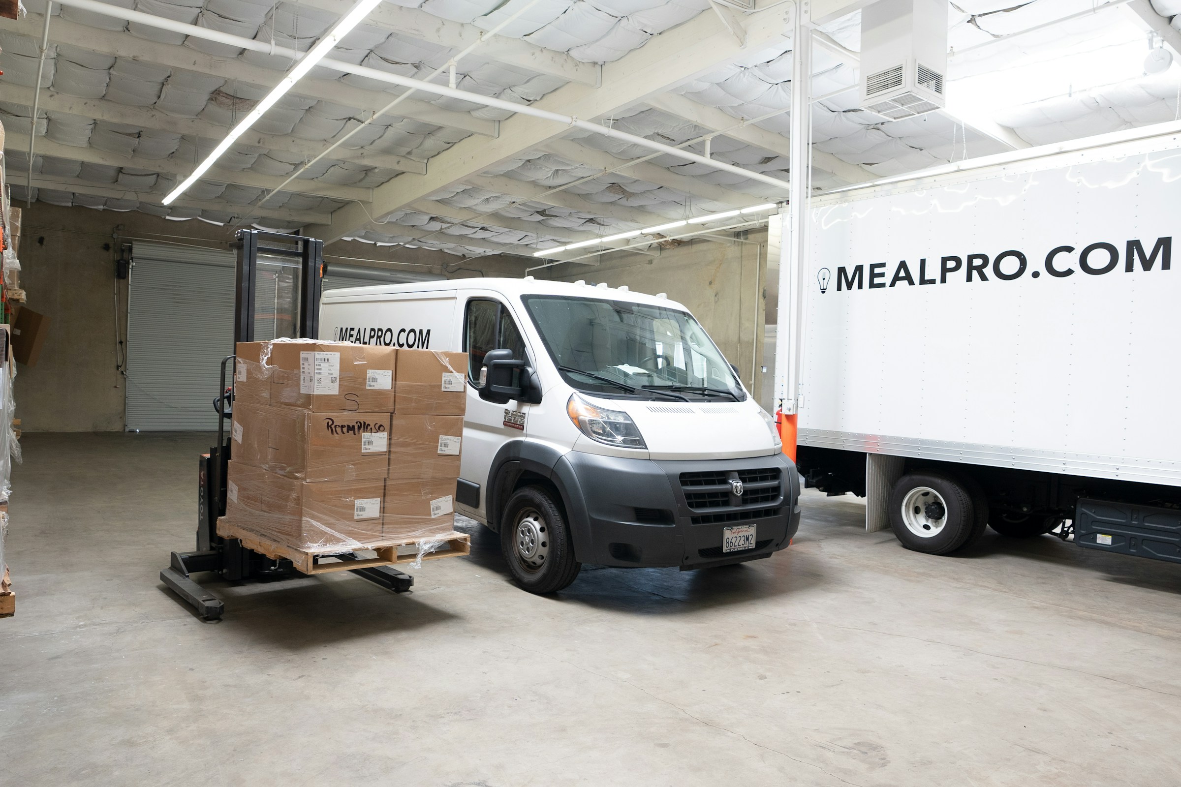 Delivery vehicles and palletized cargo inside a logistics warehouse